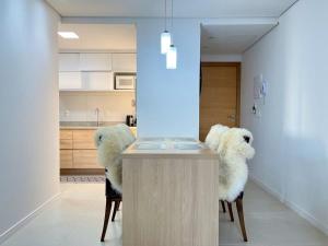 una cocina con 2 sillas de piel blanca en Apartamentos Gramado Haus no CENTRO by Achei Gramado, en Gramado