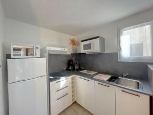 cocina con electrodomésticos blancos y nevera blanca en Appartement Saintes-Maries-de-la-Mer, 3 pièces, 6 personnes - FR-1-475-29, en Saintes-Maries-de-la-Mer