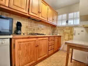 a kitchen with wooden cabinets and a white refrigerator at Appartement Saintes-Maries-de-la-Mer, 2 pièces, 6 personnes - FR-1-475-23 in Saintes-Maries-de-la-Mer