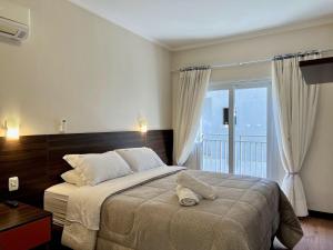 a bedroom with a bed and a large window at Apartamentos Onze1 no CENTRO by Achei Gramado in Gramado