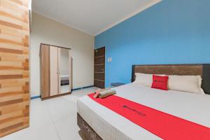 een slaapkamer met een groot bed en een rode deken bij RedDoorz Syariah @ Pangeran Suryanata Samarinda in Samarinda