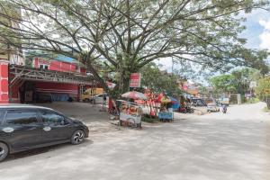 un'auto parcheggiata sotto un albero su una strada di RedDoorz Syariah @ Pangeran Suryanata Samarinda a Samarinda