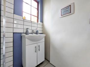 een badkamer met een witte wastafel en een raam bij Upmarket off grid cottage on organic farm in secure estate in Howick