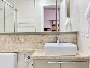 Baño blanco con lavabo y espejo en Apartamentos Loft One no CENTRO by Achei Gramado, en Gramado