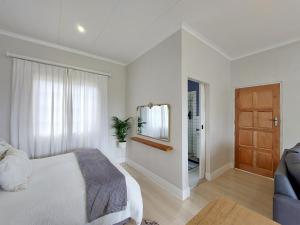 a white bedroom with a bed and a mirror at Upmarket off grid cottage on organic farm in secure estate in Howick