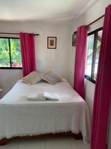 1 dormitorio con cama blanca y cortinas moradas en Great location, right downtown Puerto plata . en San Felipe de Puerto Plata