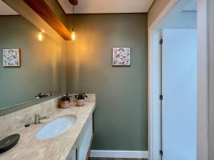 a bathroom with a sink and a mirror at Apartamentos Quinta do Palácio by Achei Gramado in Canela