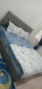 Cama con sábanas y almohadas azules y blancas en AZhomestay, en Jitra