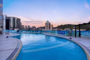 a large swimming pool with a city in the background at Guangdong Hotel (Zhuhai) in Zhuhai