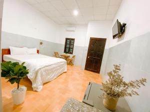 a bedroom with a bed and a table with a plant at Lac House Mui Ne in Mui Ne