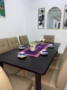 a black dining room table with chairs and flowers on it at Islamic Homestay Promenade Tanjung Lumpur in Kuantan