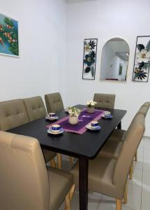 a black dining room table with chairs and a mirror at Islamic Homestay Promenade Tanjung Lumpur in Kuantan