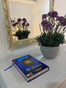 a book sitting on a table next to a vase with purple flowers at Islamic Homestay Promenade Tanjung Lumpur in Kuantan