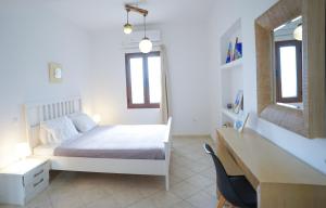 a white bedroom with a bed and a desk at Fira Central Apartments with Veranda in Fira