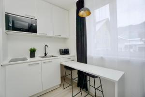 a kitchen with white cabinets and a counter with stools at Motel by Maier Götzis- kontaktloser Check-in in Götzis