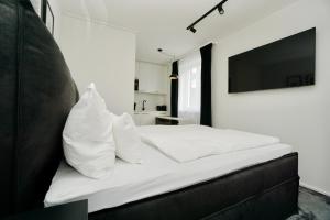 a bedroom with a bed with white sheets and a television at Motel by Maier Götzis- kontaktloser Check-in in Götzis