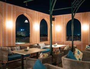 restauracja ze stołami, krzesłami i oknami w nocy w obiekcie Bur'Dera - a Boutique Luxury Hotel w mieście Dżajpur