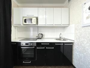 cocina con armarios blancos, fregadero y microondas en 1-комнатная квартира, центр, супермаркет Сокол en Petropavlovsk