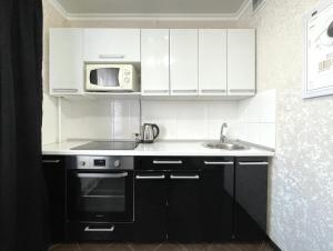 a kitchen with white cabinets and a sink and a microwave at 1-комнатная квартира, центр, супермаркет Сокол in Petropavlovsk