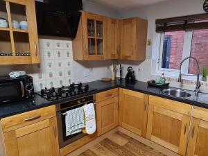 kuchnia z drewnianymi szafkami i piekarnikiem w obiekcie Spacious, 5 bed house for 9 in Chester w mieście Chester