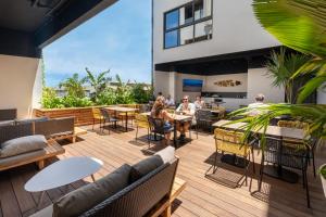 personnes assises sur une terrasse avec tables et chaises dans l'établissement Polynesian Cabins by Kon Tiki, à Papeete