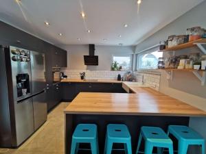 eine große Küche mit einer Holztreppe und blauen Stühlen in der Unterkunft Maison moderne et accueillante in Mackenheim