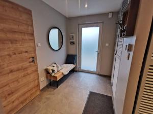 einen Flur mit einer Tür, einem Stuhl und einem Spiegel in der Unterkunft Maison moderne et accueillante in Mackenheim