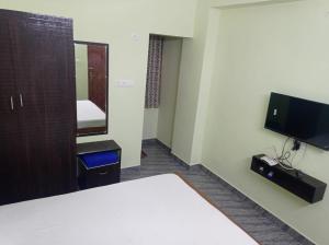 a hotel room with a bed and a tv at Hotel Sv Inn in Thanjāvūr
