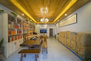 a room with a table and benches and bookshelves at Qianxun Tea House & Homestay in Wuyishan