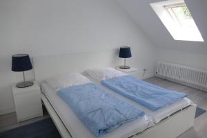 a white bedroom with a bed with blue sheets and two lamps at Baltic Nr. 24 in Scharbeutz