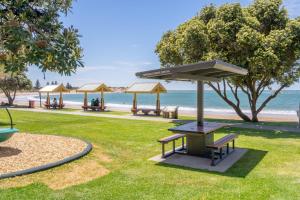 a park with benches and umbrellas on the beach at Boomer Beach Retreat- Pet and Family Friendly in Port Elliot