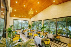 un restaurante con mesas y sillas en una habitación con ventanas en Perolas Villas Resort Powered by ASTON, en Phan Thiet