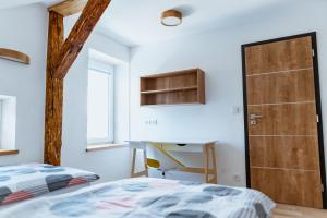 a bedroom with a bed and a desk and a door at Apartmány Jabloneček in Jablonec nad Jizerou