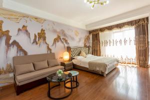 Dalian Hong Xi Yuan Apartment Wanda Plaza في داليان: غرفة نوم بسرير واريكة وطاولة