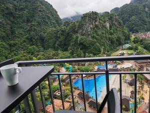 a view from the balcony of a resort with a cup of coffee at Cozy Suite with 270 Degree Mountain and Theme Park Views in Ipoh