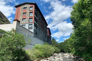 a building sitting on the side of a river at Apartamentos Canillo 3000 in Canillo