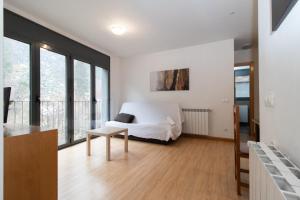 a white bedroom with a bed and a table at Apartamentos Canillo 3000 in Canillo
