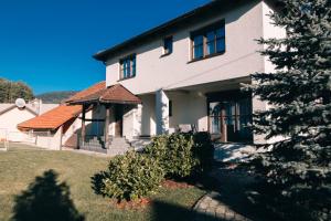 a white house with a tree in front of it at Kuca za odmor M11 in Kupres