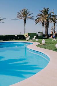 a swimming pool with palm trees in the background at Hotel Subur Maritim in Sitges
