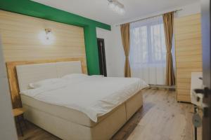 a bedroom with a white bed and a green wall at Altitude Guest House Ranca in Ranca