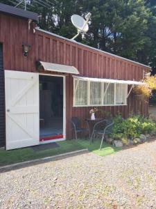 a building with a garage with a table and chairs at La Petite Ferme Studio Kerikeri in Kerikeri