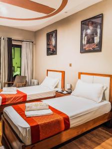 Habitación de hotel con 2 camas y mesa en Valiha Hotel Antananarivo en Antananarivo