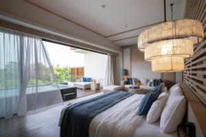 a bedroom with a large bed and a large window at Cape Nidhra Hotel in Hua Hin