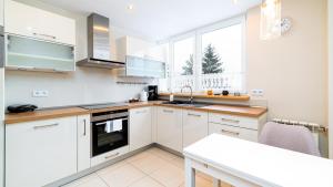 a kitchen with white cabinets and a table in it at Apartamenty Sun & Snow Korczaka in Świeradów-Zdrój