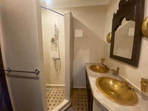 uma casa de banho com 2 lavatórios dourados e um chuveiro em Riad Al Karama em Marrakech