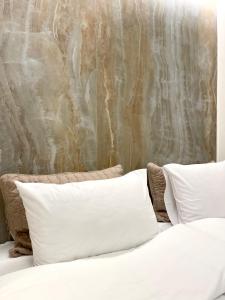 a bed with white pillows in front of a wall at Aesthesis Arxontiko Luxury Rooms in Myrina