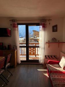 sala de estar con una gran puerta de cristal que da a un balcón en Le Bouquetin - Immeuble Le Pluton, en Les Deux Alpes