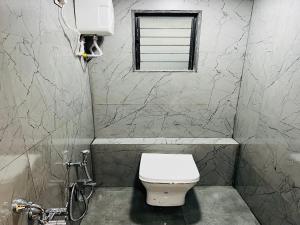 ein Bad mit einem weißen WC und einem Fenster in der Unterkunft Hotel New City Light in Surat