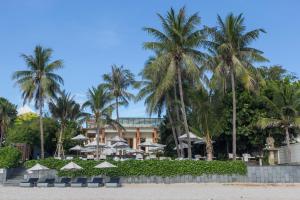 um resort com palmeiras e guarda-sóis na praia em Cape Nidhra Hotel em Hua Hin