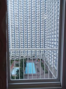 a view of a large building from a window at 1 BR with poolside view balcony in Manila